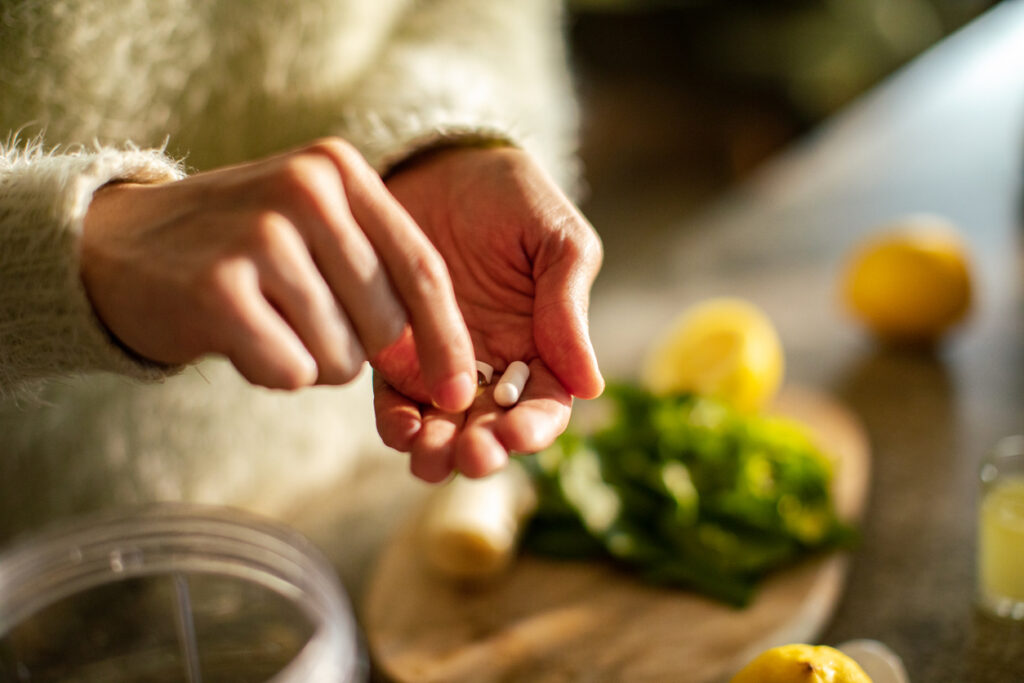 Young woman taking a health supplement in the kitchen -